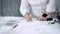 Close up of female hands with pin cushion and pencil drawing outline. Image of body of a woman in white blouse and skirt