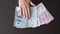 Close up of female hands puts on the table and collecting a fan of different currency. Euro, dollar, hryvnia, rubles