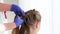 Close-up of female hands in rubber gloves braiding a pigtail from the hair of a child.