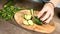 Close-up of female hands slicing cucumbers on a stroller on a cutting board next to chopped mint leaves. Healthy and