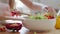 Close-up female hands stirring with wooden spoon ingredients vegetables in fresh delicious salad, unrecognizable family