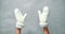 Close up female hands in white woolen mittens waving on a gray background