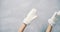 Close up of female hands in white woolen mittens waving from side to side on a gray background