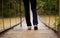 Close-up of female hiker feet walking on forest bridge across river. Active woman backpacker traveling