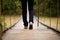 Close-up of female hiker feet walking on forest bridge across river. Active woman backpacker traveling