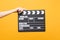 Close up female holding in hand classic director clear empty black film making clapperboard isolated on trending yellow