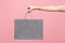 Close up female holds in hand grey clear empty blank craft paper gift bag for purchases after shopping on