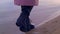Close up of female leather black boots walking on a sandy shore and the water edge. Stock footage. Details of a young