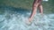 Close-up of female legs. A girl with bare feet walks along the seashore, being feet in the water.