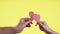 Close up of female and male hold in hands little hearts isolated on yellow background. Valentines day and Like blogging
