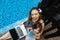 Close-up of female mother, daughter and laptop on background of swimming pool