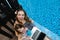 Close-up of female mother, daughter and laptop on background of swimming pool