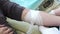 Close-up of female nurse bandaging hand of male patient