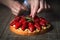 Close up of female pastry chef`s hand decorating  top of delicious French strawberry cake