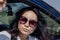 Close-up of a female portrait of a young attractive Asian woman in a car. Charming Korean in stylish sunglasses outdoors