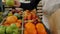 Close-up of a female saleswoman in an apron putting oranges in an eco bag.