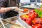 Close up female seller hands holding grilled bell peper in the takeaway food container. A buffet on a holiday on the street food c