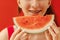 A close-up of a female teenager mouth with dental braces and a piece of delicious watermelon. The smile of a cute teen girl eating