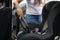 Close-up of female using portable vacuum cleaner in her car. Baby ca seat cleaning. Woman vacuuming seats. Dust and dirt