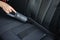 Close-up of female using portable vacuum cleaner in her car. Car interior cleaning. Woman vacuuming seats. Dust and dirt