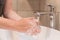 Close up of female washing hands with soap in bathroom