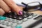 close up of a female woman pressing on calculator button with eyeglasses and paperwork in background. accounting and bookkeeping