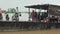 Close-up on ferry boat leaving pier with passengers sitting under wood and sheet-metal shelter or standing outside