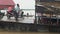 Close-up on ferry boat leaving pier with passengers sitting under wood and sheet-metal shelter or standing outside