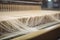 Close-up of fiberglass strands being woven together on a high-speed loom in a production facility