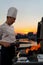 Close-up of filet mignon vegetables and meat on a bbq grill on a skyscraper rooftop at sunset. Fire in the barbecue