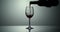 Close-up of filling wine glass with white wine in super slow motion. Pouring gold wine into goblet at blue background