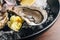 Close up Fine de Claire Oyster and lemon served in black bowl with ice on wooden table