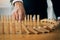 Close up finger businessman stopping wooden block from falling in the line of domino with risk concept