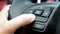 Close up of finger pressing the audio control buttons to increase or decrease the volume on the steering wheel when driving.