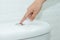 Close up of finger pushing a flush toilet button for cleaning. -