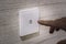 close-up finger turns on the light on the touch switch. A white modern light switch on a white wall. modern design