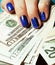 Close up fingers with deep blue creative pattern manicure holding dollars