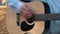 Close-up fingers of a man playing the acoustic guitar outdoors