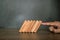 Close-up fingers prevent the wooden block from falling domino