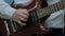 Close-up of the fingers of a teenager playing a brown electric guitar. The guy pulls the strings on a musical power tool