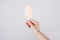 Close up first person cropped view photo of hand arm holding delicious yummy tasty sugary ice cream bar isolated grey background