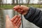 Close-up of a fishing rod, line and a hook with worm in hands. River and forest in the background