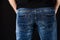 Close up of a fit and sexy male butt in classic blue jeans and black t-shirt against black background