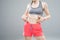 Close up of fit woman`s torso with her hands on hips. Female with perfect abdomen muscles on grey background