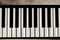 Close-up of flat piano keyboard, top view. Piano keys on textured concrete background
