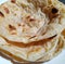 Close up of flat slices of baked roti bread on white background