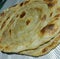 Close up of flat slices of baked roti bread on white background