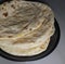 Close up of flat slices of baked roti bread on white background