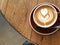 Close up flat white latte art on a wooden table against a concrete floor from above