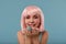 Close up of a flirtatious female model on blue background wearing a pink wig holding different kinds of candies. Pretty